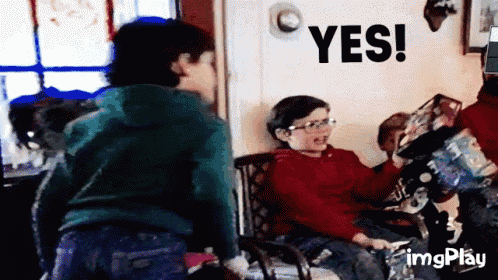 a boy in a red shirt is sitting in a chair with a yes sign above him