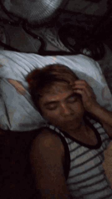 a man laying on a bed with yellow leaves coming out of his hair