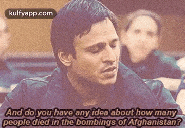 a man is sitting in a classroom talking to a group of people .
