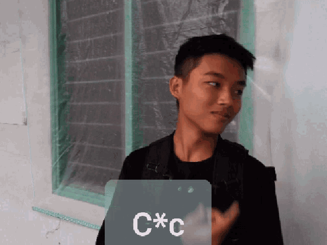 a young man is standing in front of a window with a sign that says c * c