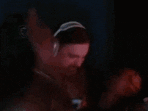 a man with a beard wearing headphones is dancing in the dark .