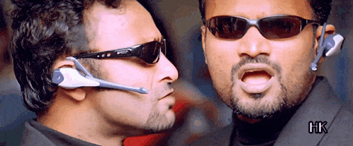 two men wearing sunglasses and a headset with hk written on the bottom right