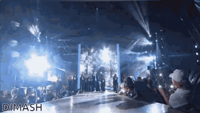 a group of people are standing on a stage and the word dimash is on the bottom right