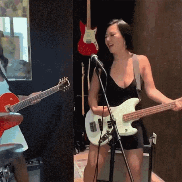 a woman singing into a microphone while a man plays a guitar