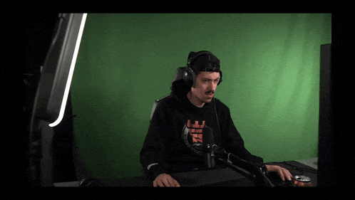 a man wearing headphones is sitting in front of a green screen and has a shirt that says i 'm sorry