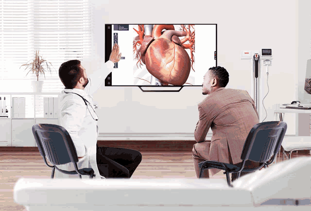 a doctor shows a patient a picture of a heart on a television screen
