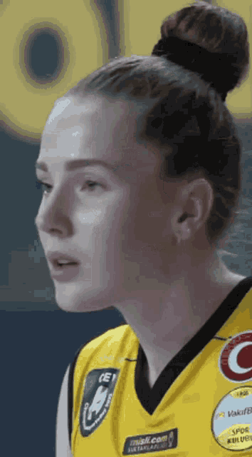 a close up of a woman 's face wearing a yellow shirt that says ' mini.com ' on it