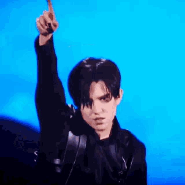 a man is covering his face with his hand while wearing a black jacket .