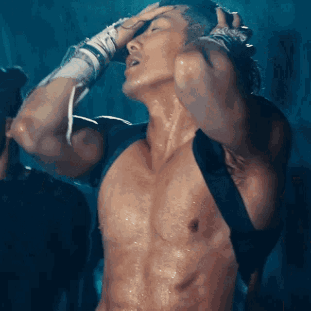 a man without a shirt is sweating while holding his head