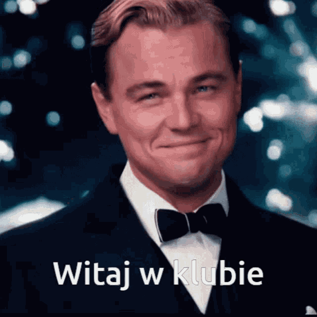 a man wearing a tuxedo and bow tie is smiling with the words witaj w klubie behind him