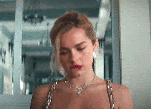 a woman wearing a necklace and earrings is looking down