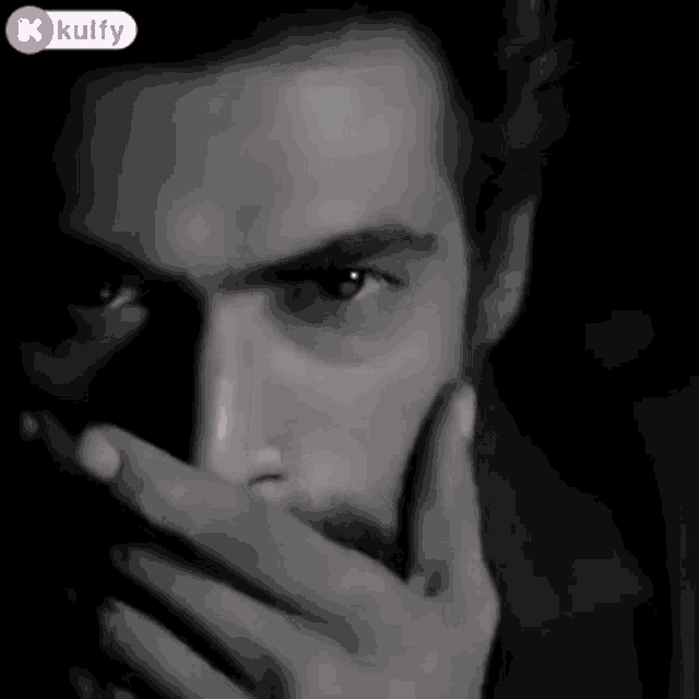 a close up of a man covering his mouth with his hand
