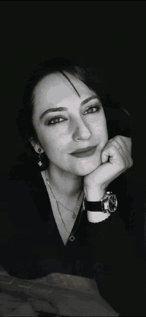 a woman wearing a black shirt and a watch is smiling