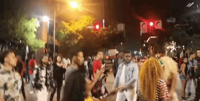 a crowd of people walking down a street at night