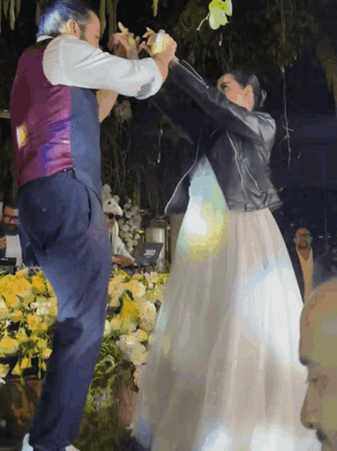 a man in a purple vest is dancing with a bride in a white dress