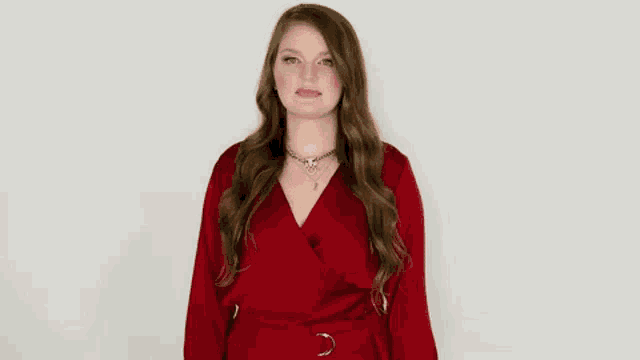a woman in a red dress is standing with her arms outstretched and screaming .