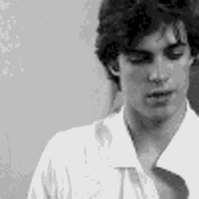 a black and white photo of a young man wearing a white shirt .