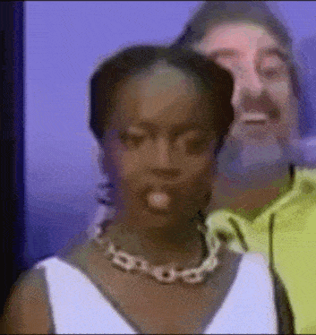 a woman wearing a necklace is standing next to a man wearing a yellow jacket .