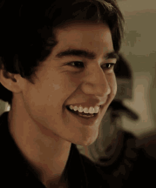 a close up of a young man 's face with a smile