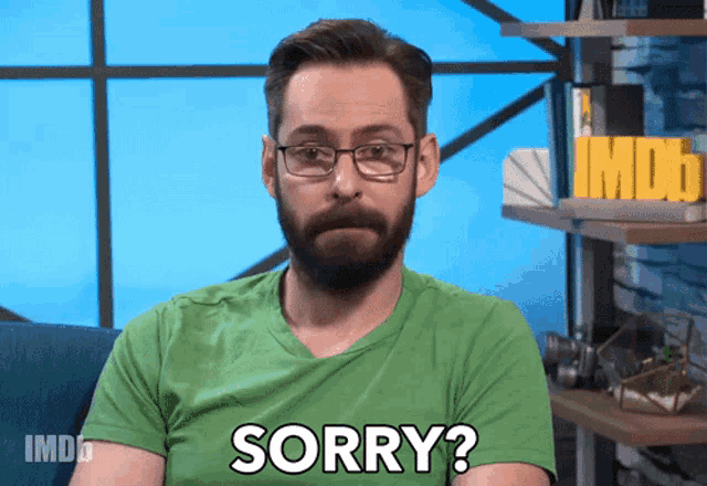 a man wearing glasses and a green shirt says " sorry "