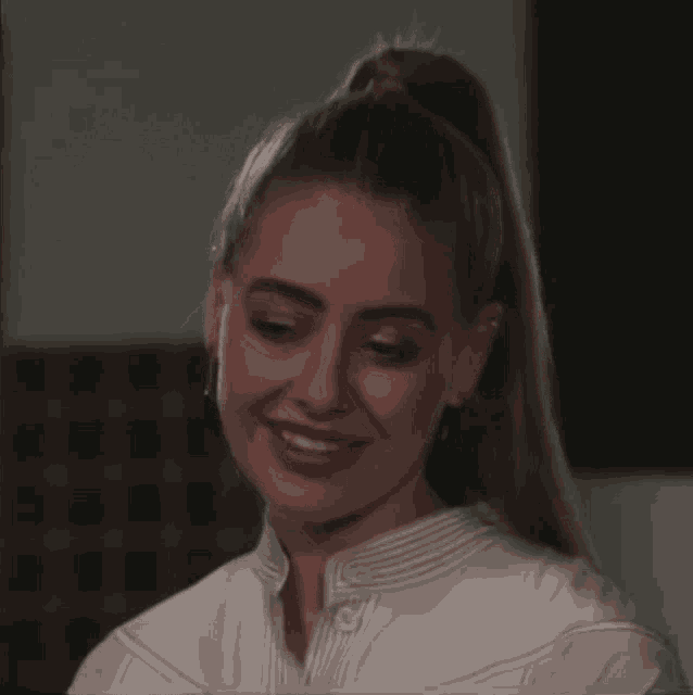 a woman with a ponytail and a white shirt is smiling .