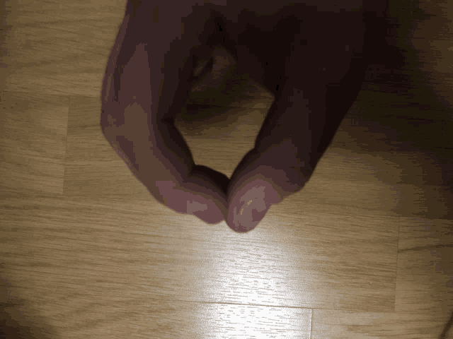 a close up of a person 's hand on a wood floor