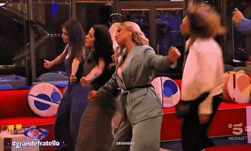 a group of people are dancing in front of a sign that says grandefratello on it