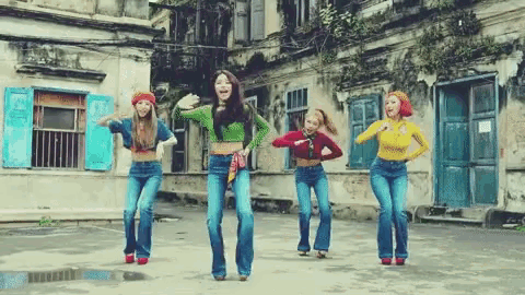 a group of girls are dancing in front of a building