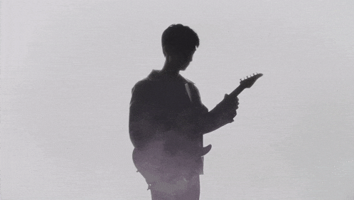 a silhouette of a man holding a guitar in his hand