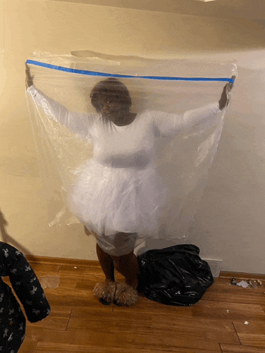 a woman in a white dress is standing under a clear plastic bag