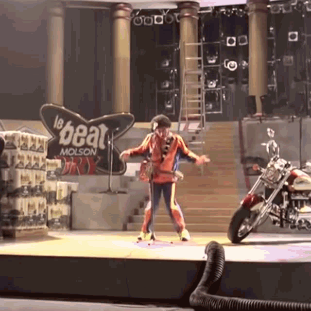 a man stands on a stage in front of a sign that says " molson "