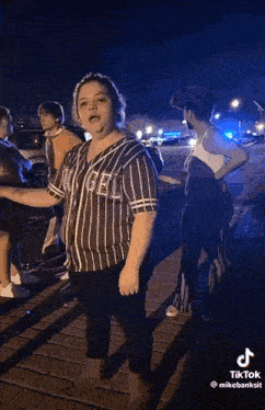 a woman in a striped shirt with the word angels on it is standing next to a group of people .