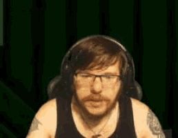 a man with a beard and glasses is wearing headphones and a tattoo on his arm .