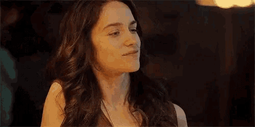 a woman with long curly hair is smiling and looking at the camera .