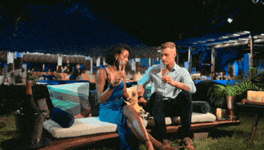 a man and a woman are sitting on a couch holding champagne glasses