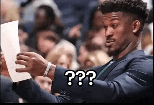 a man in a suit is holding a piece of paper and says " ?? " on the bottom