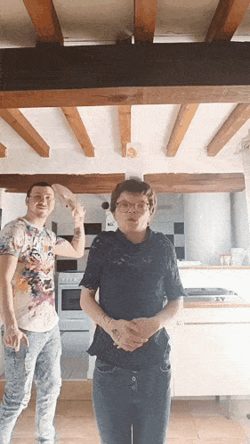 a man and a woman are standing in a kitchen with wood beams