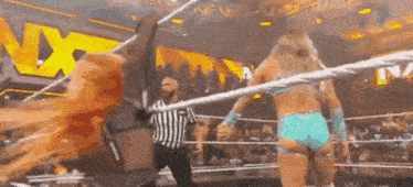 two women are wrestling in a wrestling ring with a referee standing behind them .