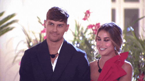 a man in a suit and a woman in a red dress are standing next to each other and smiling
