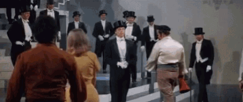 a group of men in tuxedos and top hats are standing in a room .