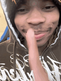 a close up of a person wearing a hoodie with a finger in their mouth
