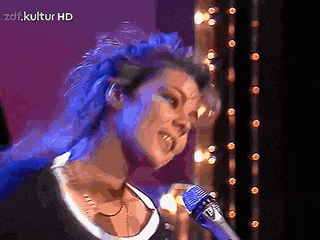a woman singing into a microphone with a zdf.kultur hd logo behind her