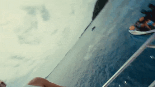 a person is sitting on the edge of a boat in the water .