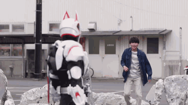 a man in a blue shirt is standing in front of a building while a man in a white costume is standing behind him