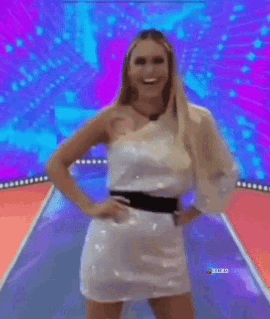 a woman in a white dress is walking down a runway in front of a screen that says ' sxed '