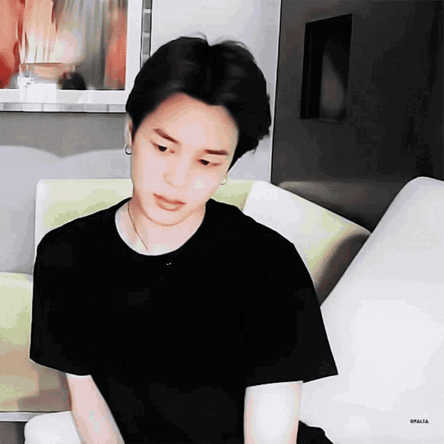 a man in a black shirt sits on a couch