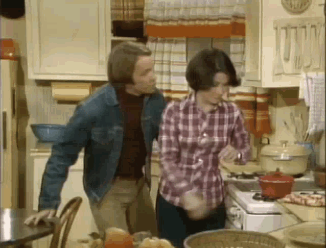 a man and a woman are standing in a kitchen .