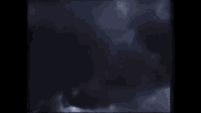 a close up of a person 's face in a dark room with smoke coming out of their mouth .