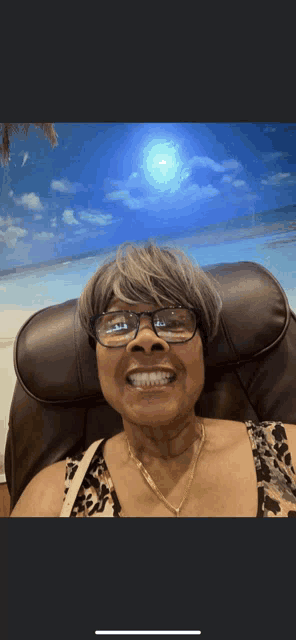 a woman wearing glasses is smiling in front of a beach background