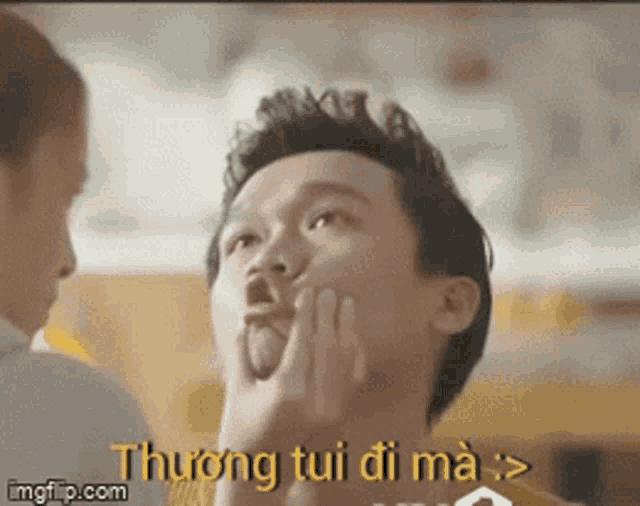 a man is making a funny face with his hand on his face while a woman watches .